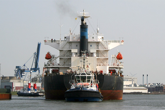 Ein großes Seeschiff wendet mit Schlepperhilfe im Bremer Industriehafen
