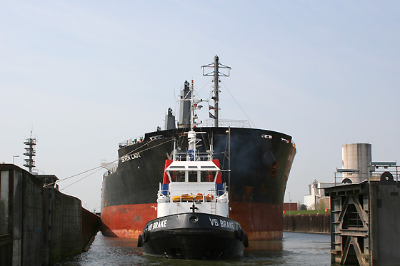 Ein großes Seeschiff verlässt mit Schlepperhilfe die Schleuse Oslebhausen